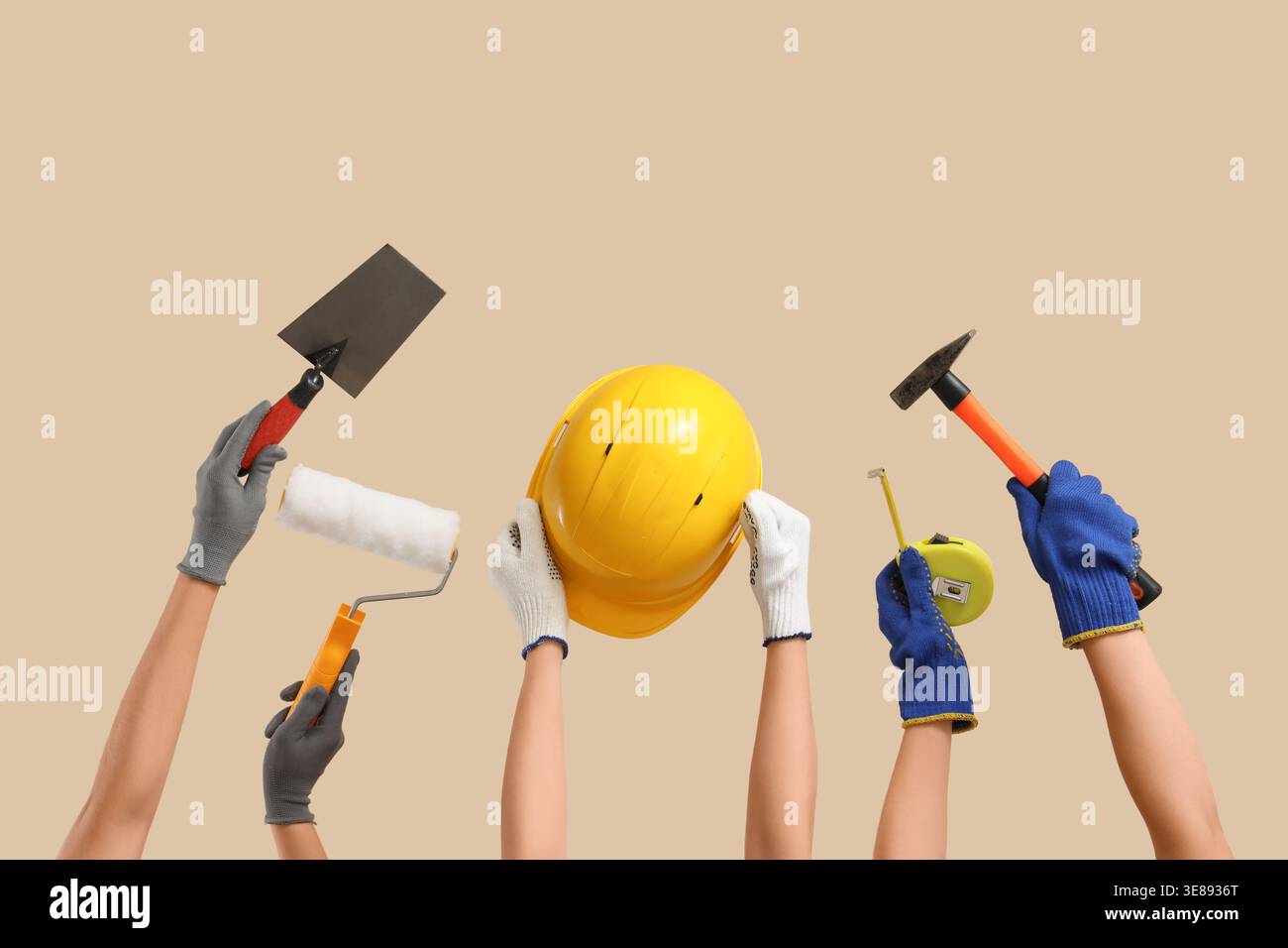 Hands with hardhat and construction tools on beige background Stock Photo