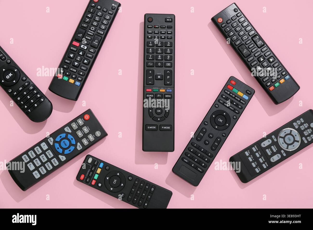 Different modern TV remote controls on pink background Stock Photo