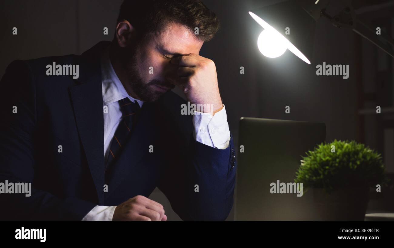 Exhausted businessman doing report on laptop, having problems Stock Photo
