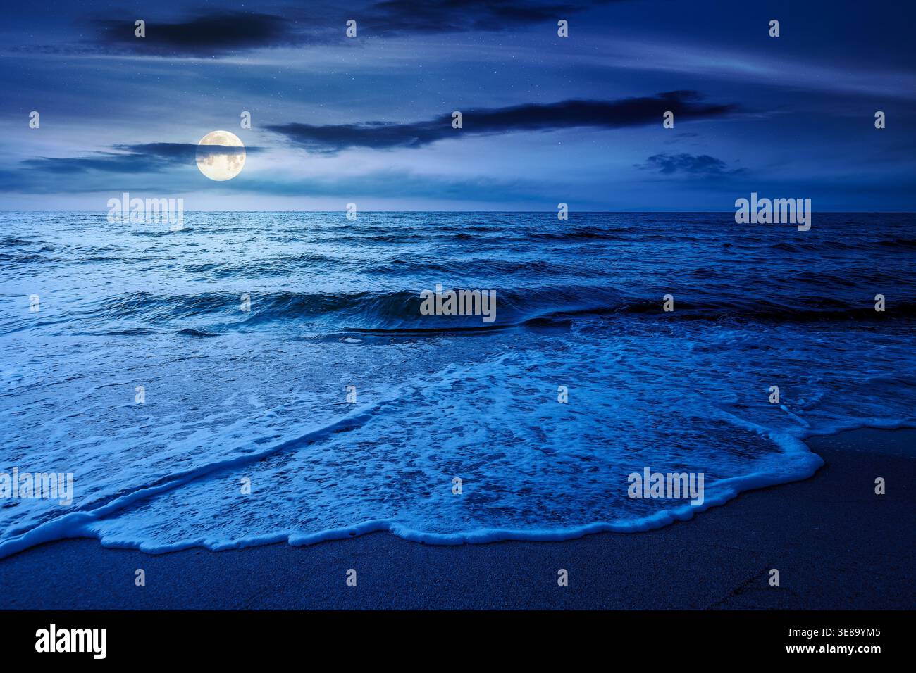 autumn vacation at the sea at night. full moon over beautiful seascape. calm waves wash the sandy beach. image with cloudy sky above horizon. mysterio Stock Photo