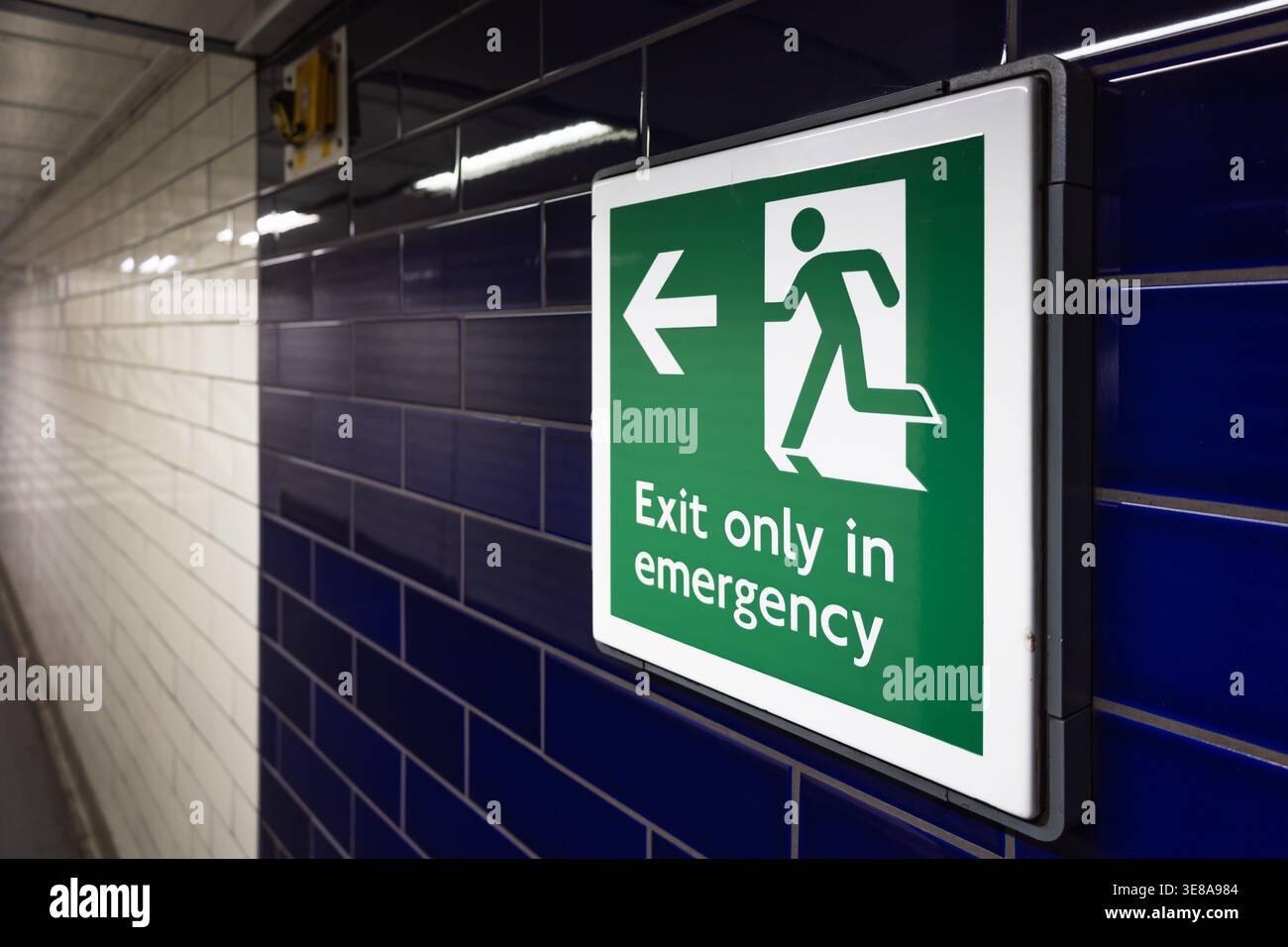 Emergency exit sign in an underground corridor Stock Photo