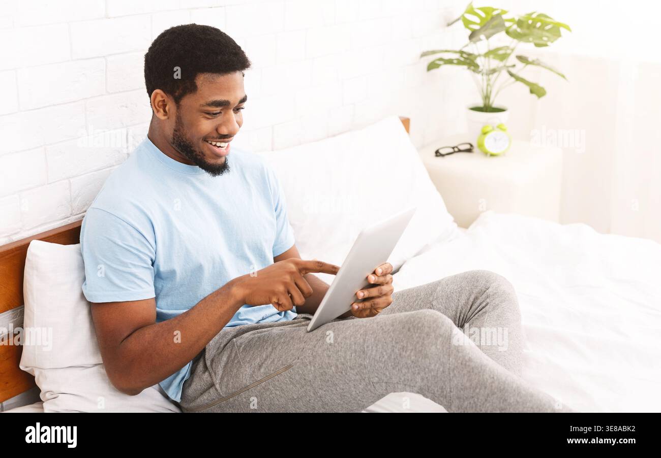 Relaxed casual man using smartphone in bed Stock Photo