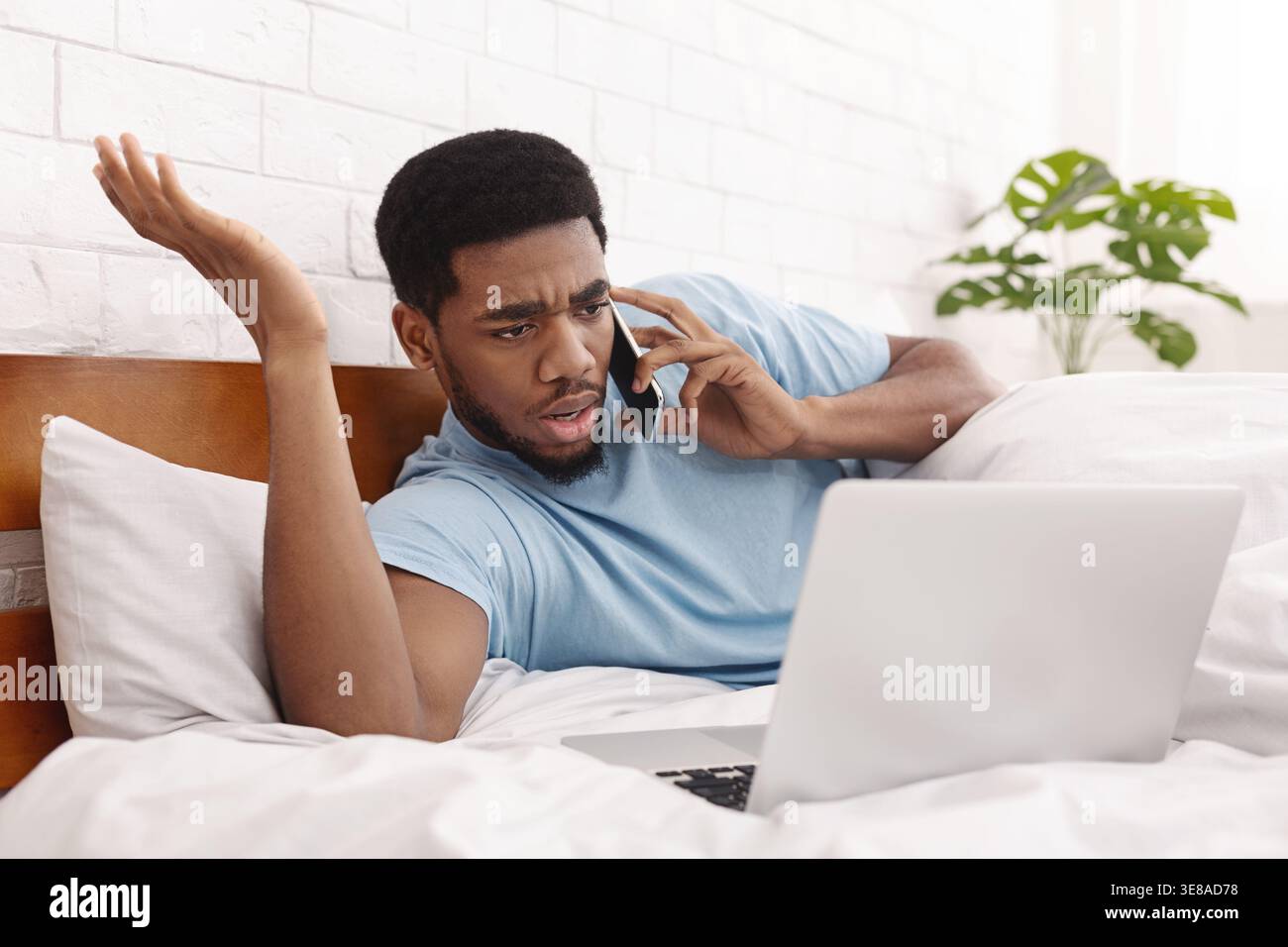 Angry man having problems with laptop talking on mobile phone Stock Photo