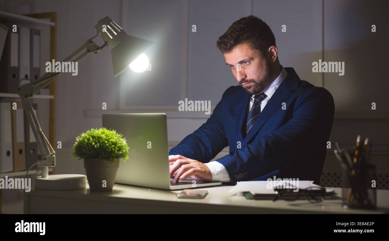 Businessman working on laptop in dark office Stock Photo