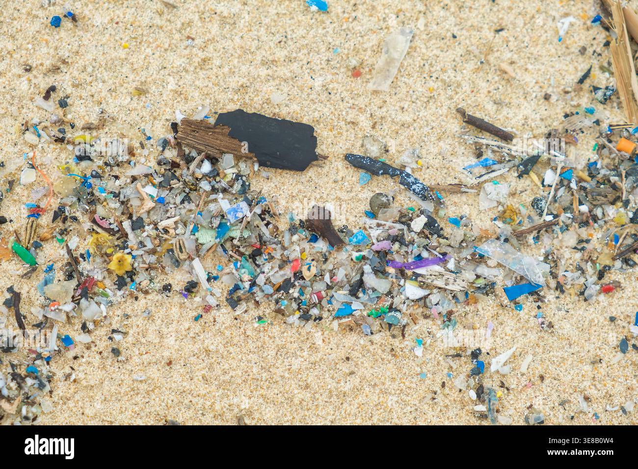 Close up of microplastic fragments mixed with sand on tropical beach on Phuket island, Thailand. Garbage and trash on polluted beach. Environmental Stock Photo