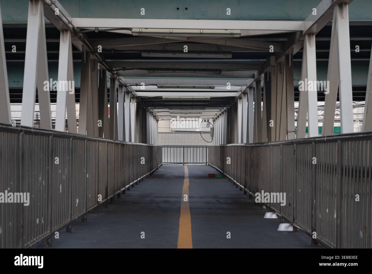 Bangkok, thailand - Apr 5, 2022 - Framed by a symmetrical array of weathered white trusses, this industrial pedestrian overpass stretches forward in a Stock Photo