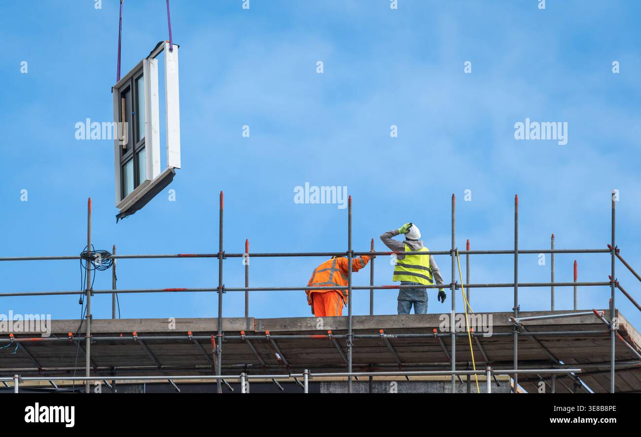 Construction workers at modern high-rise building site, urban development and engineering industry concept Stock Photo