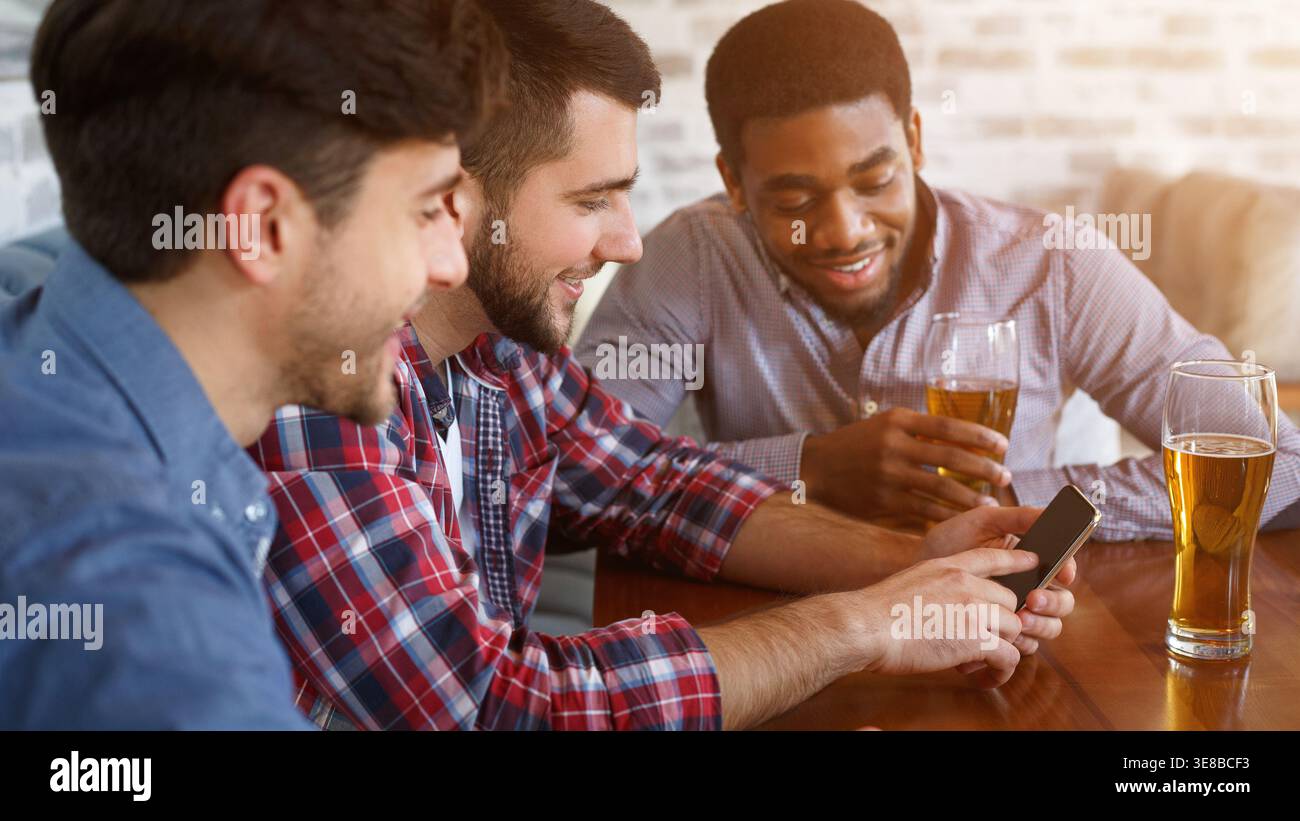 Best friends using smartphone and drinking beer Stock Photo