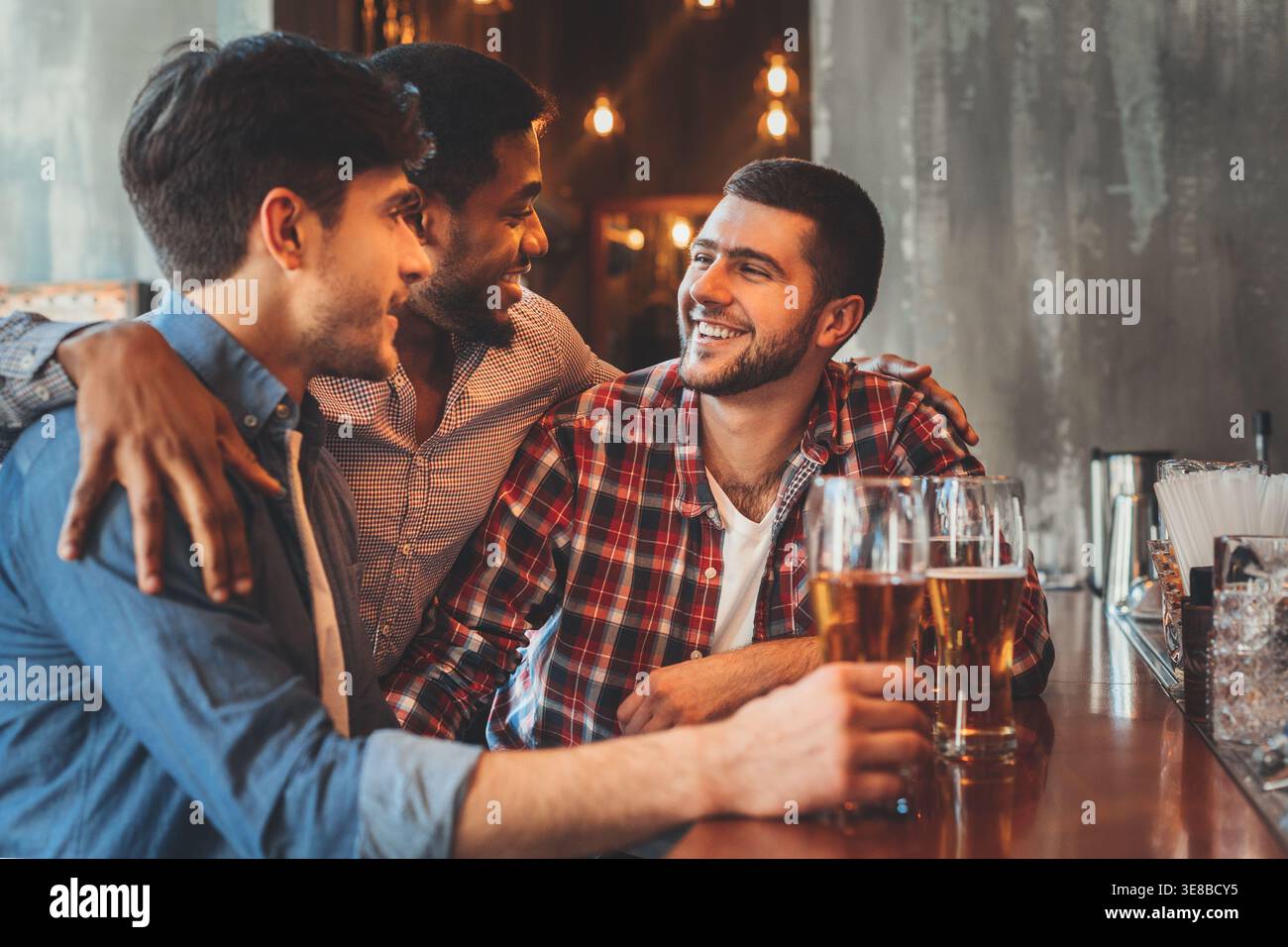 Old friends drinking beer and talking in pub Stock Photo