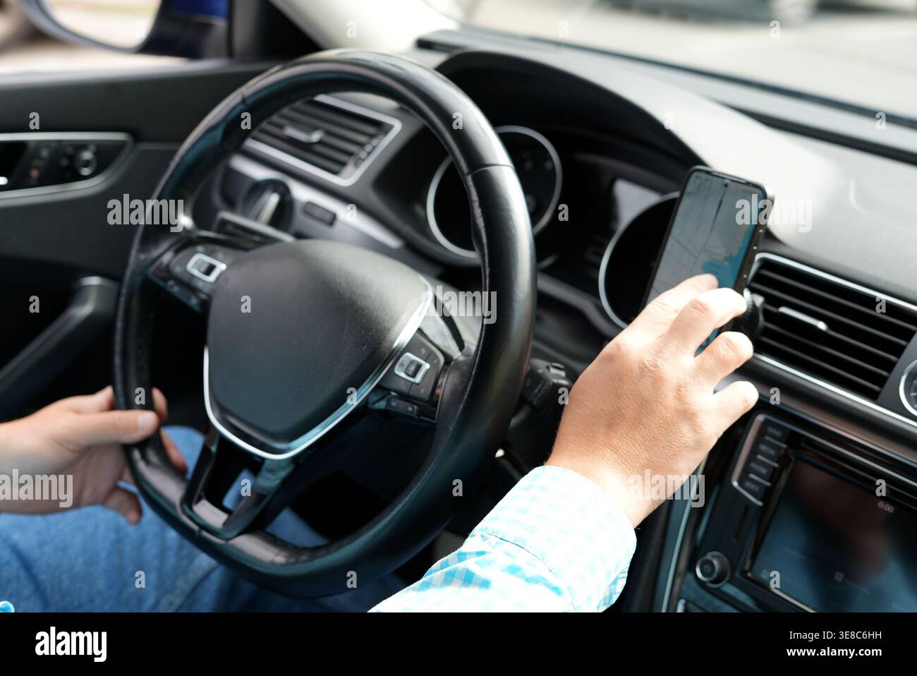 Driver using smartphone navigation while driving car interior Stock Photo