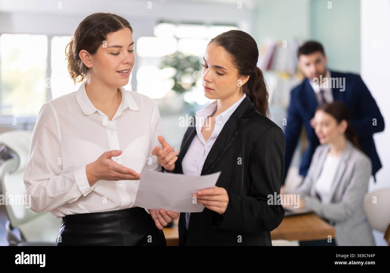 Two qualified female employees discussing work tasks Stock Photo
