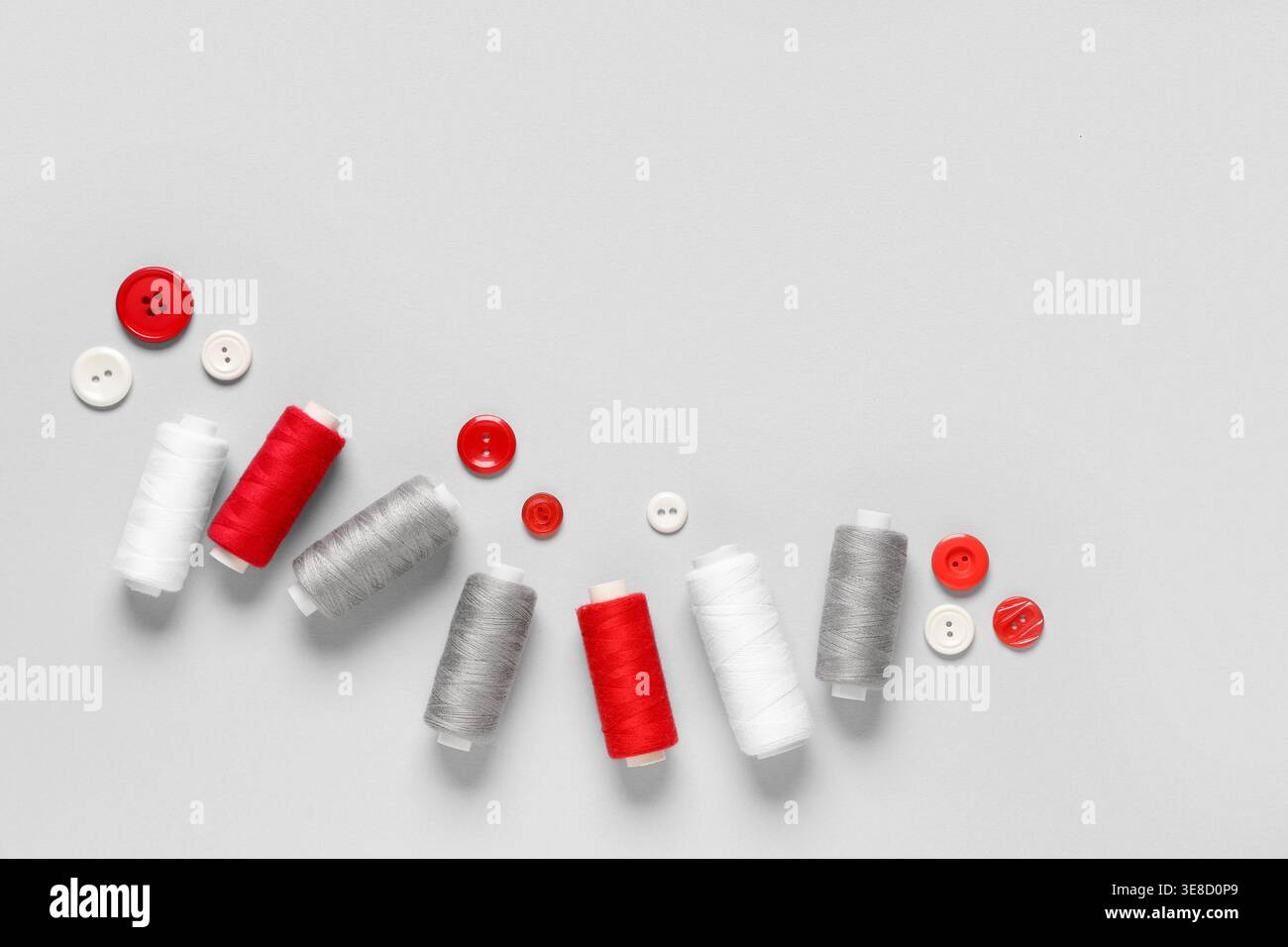 Thread spools with buttons on grey background Stock Photo