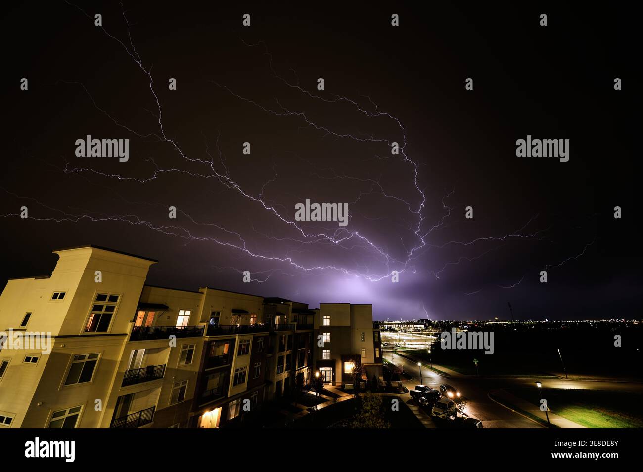 Lightning flashes beyond an apartment building as a thunderstorm passes ...