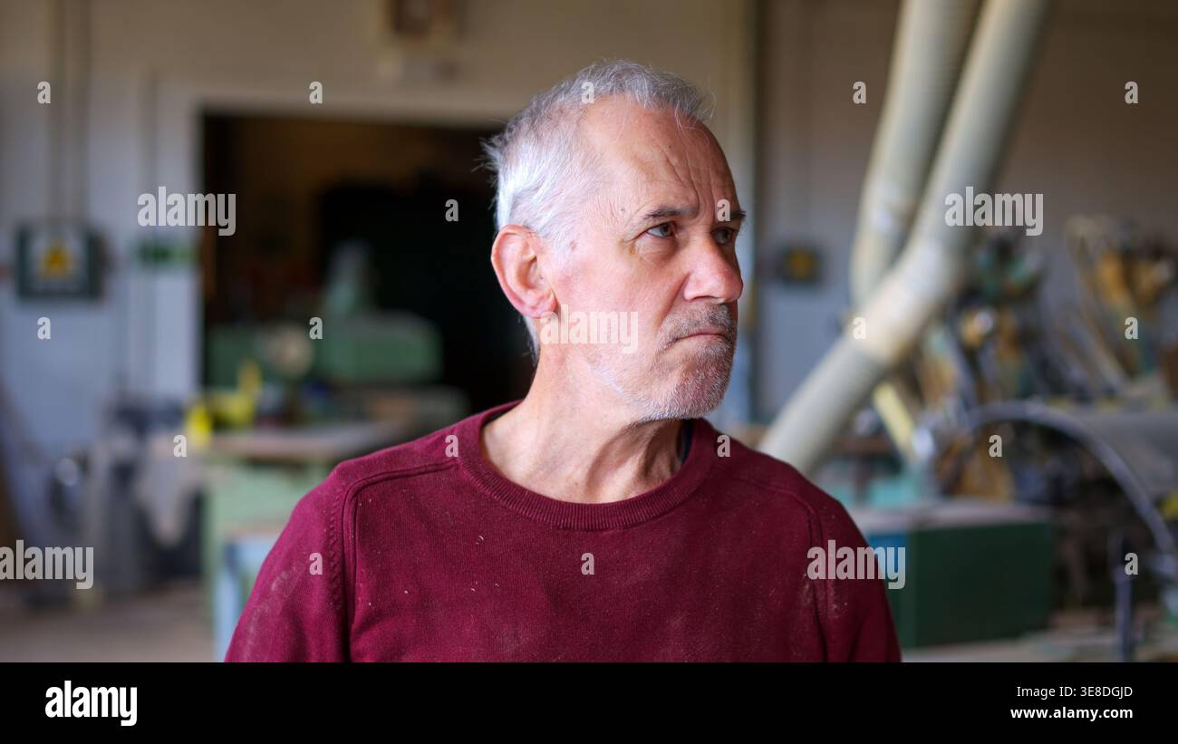 Senior man working as carpenter in workshop looking focused Stock Photo