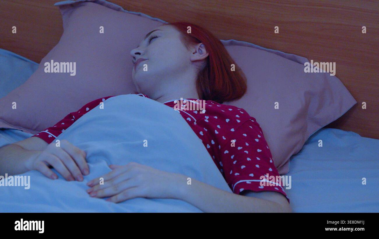 Young woman sleeping peacefully in a comfortable bed Stock Photo