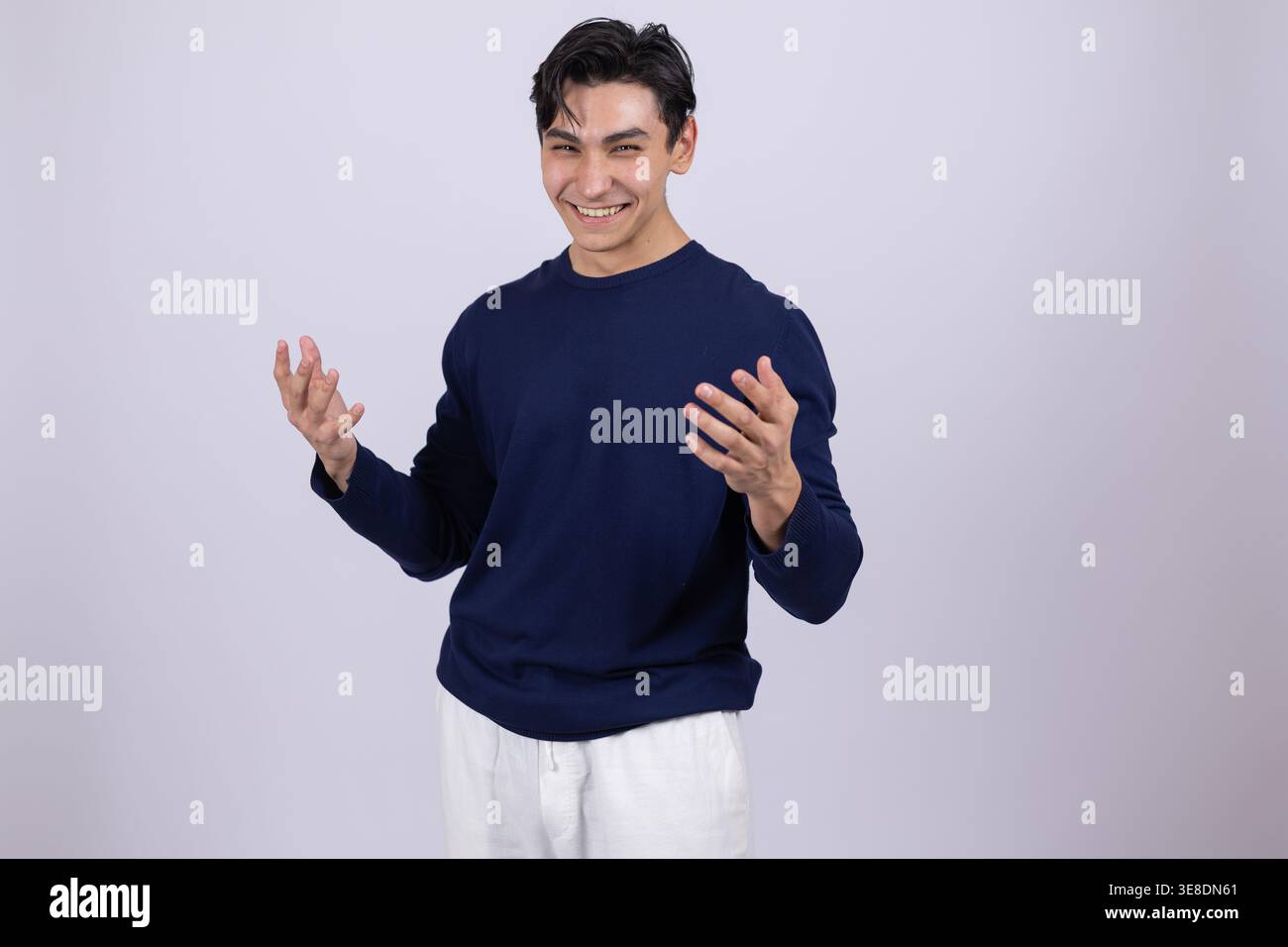 Laughing man in blue sweatshirt with open arms in studio Stock Photo