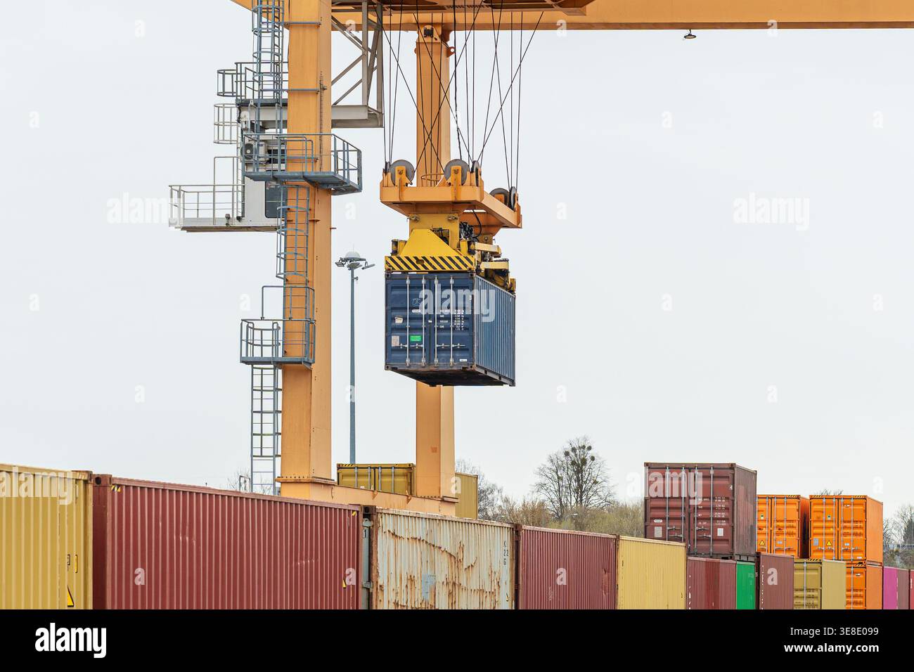 Gantry crane lifting a blue shipping container at an intermodal ...