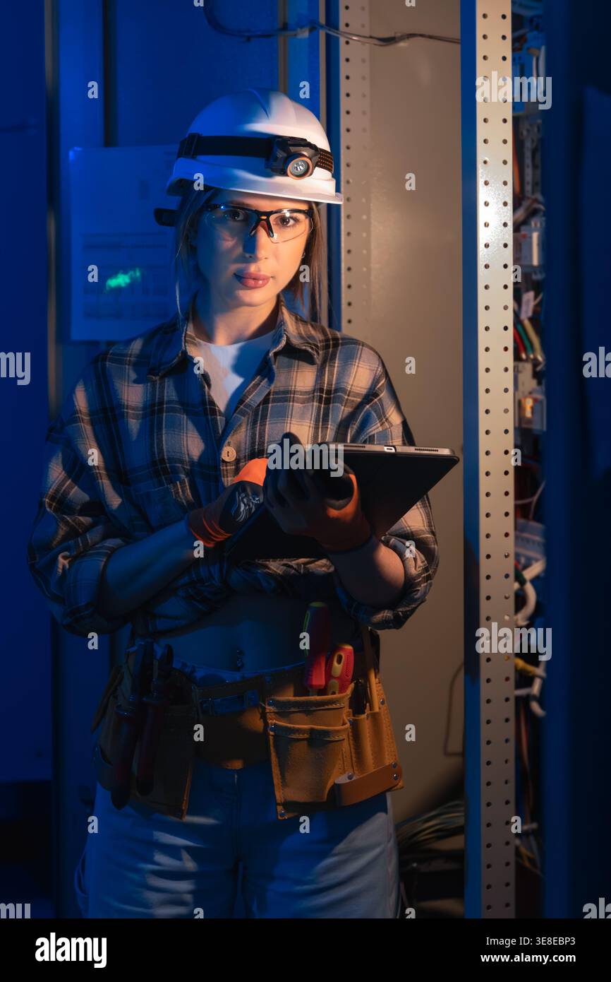 Electrical specialist using tablet near industrial switchboard panel. Technical inspection. Stock Photo