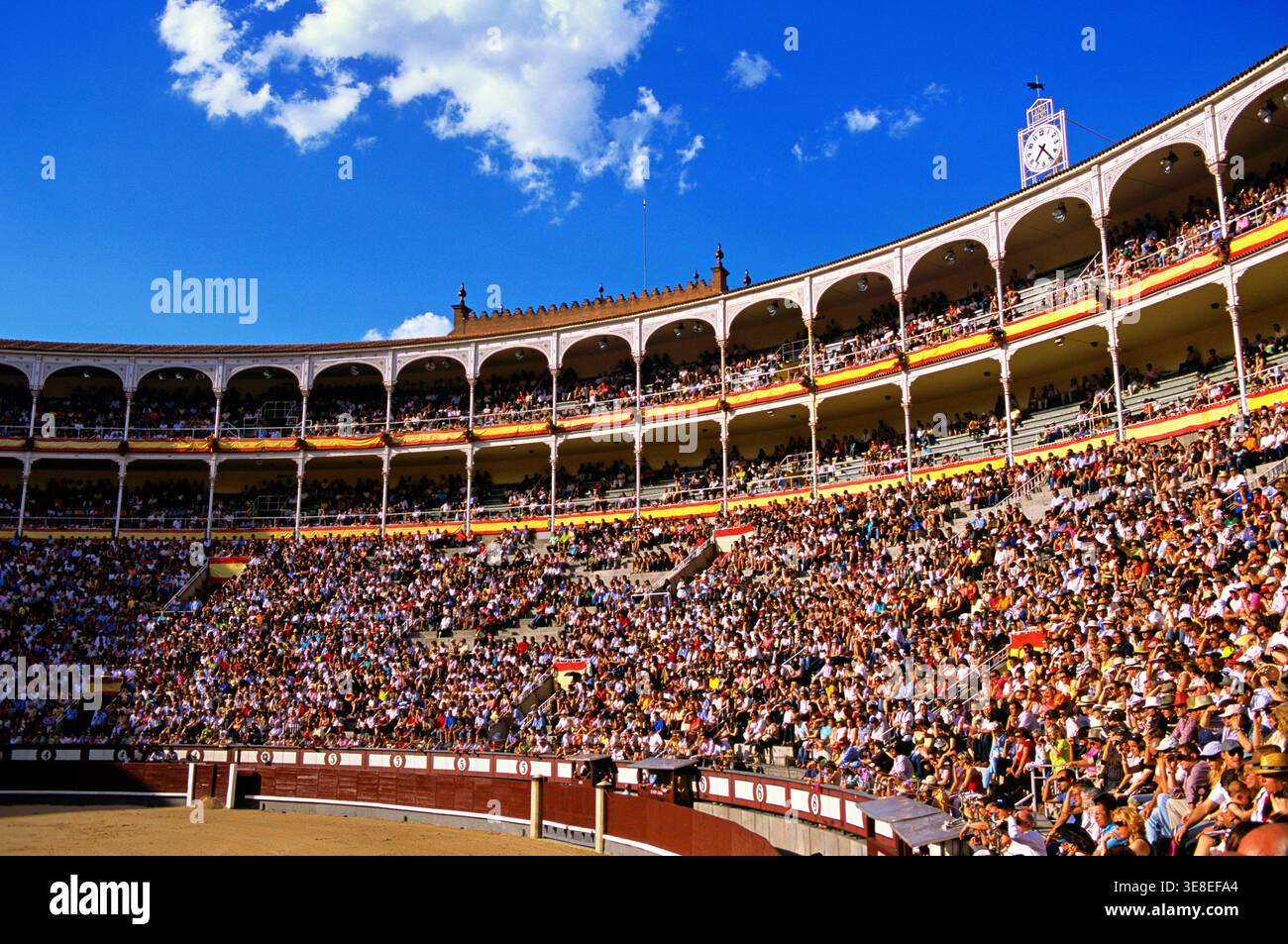 Many people fill the seats of Las Ventas Bullring in Madrid. They are attending a bullfighting event on a clear day. Stock Photo