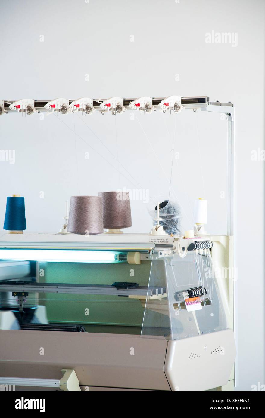 Industrial knitting machine with multiple yarn cones feeding threads ...