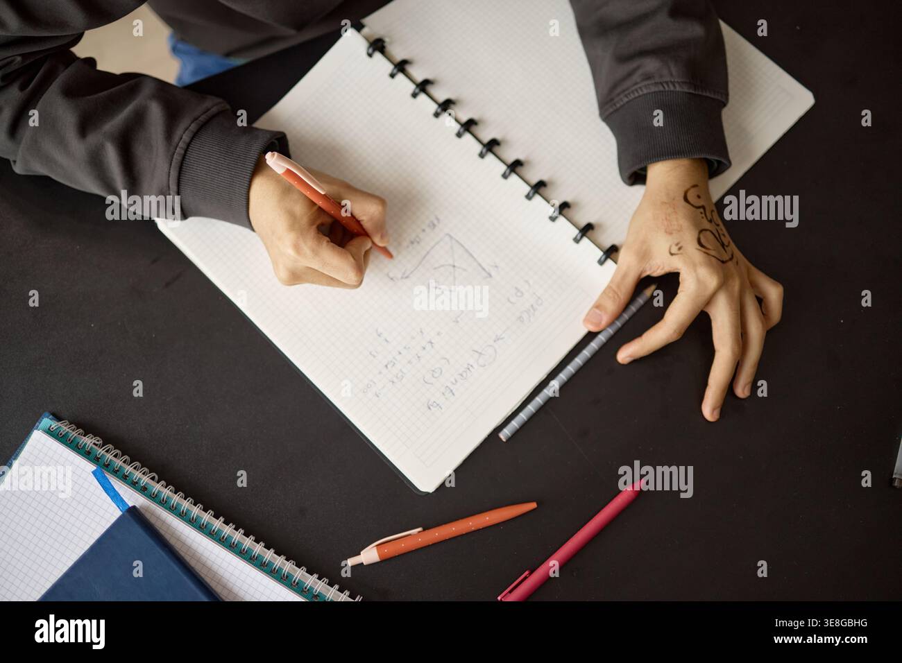 Teenager Writing Math Notes in Notebook for School Learning Stock Photo