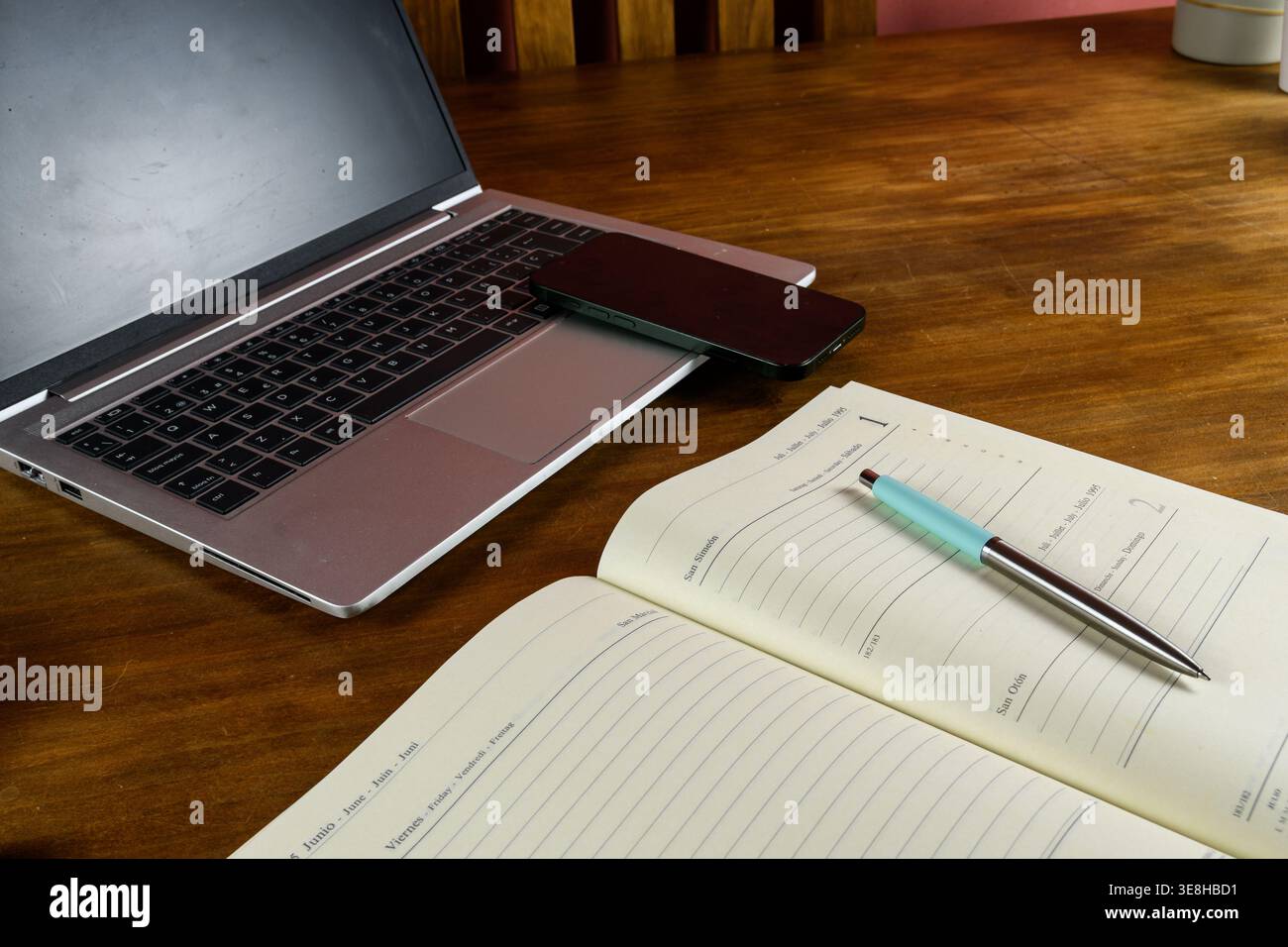 Smartphone placed on laptop keyboard, representing pause, multitasking and modern digital workflow. Stock Photo