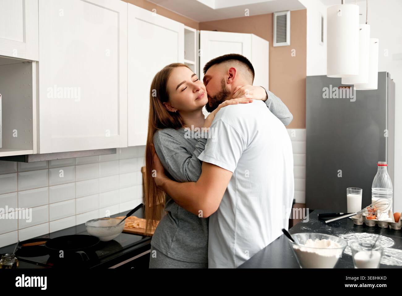 Young couple hugging during cooking at home. Concept of love and intimacy. Stock Photo