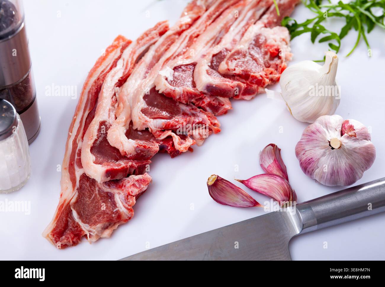 Raw lamb chops on kitchen table with garlic, arugula, spices Stock Photo
