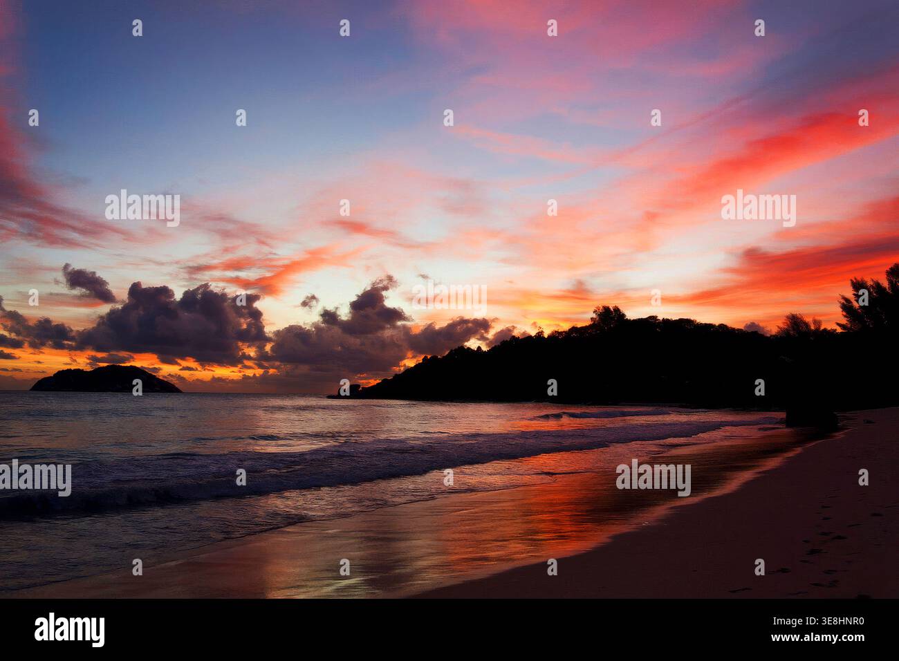Colorful sunset over tropical coastline with waves on Mahe Island, Seychelles Stock Photo