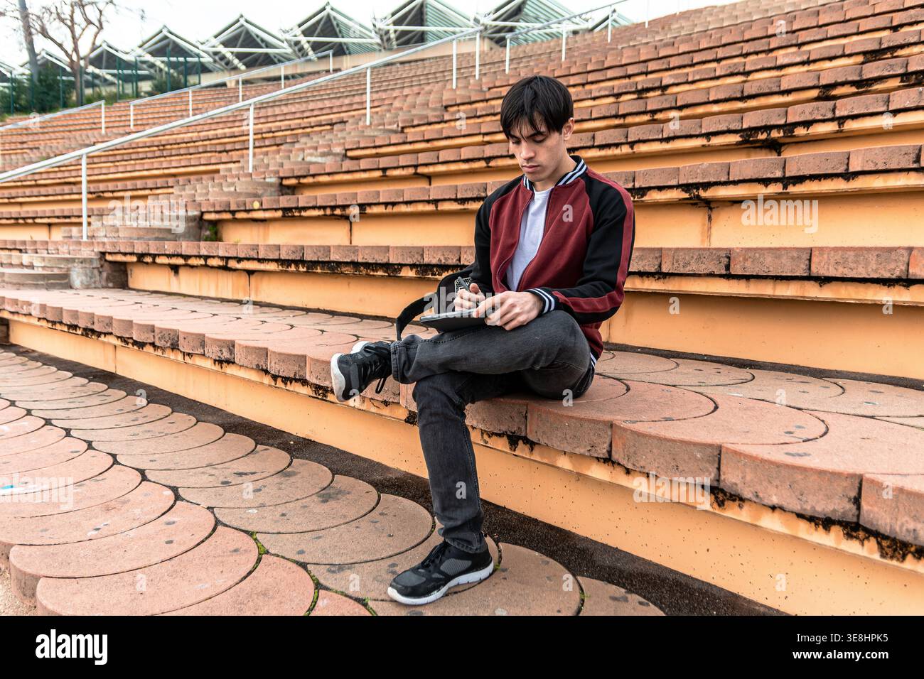 Young man studying with tablet on stadium steps Stock Photo