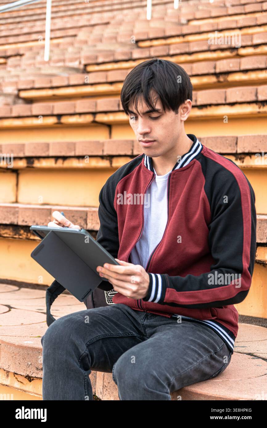 Young man studying drawing on tablet outdoors Stock Photo