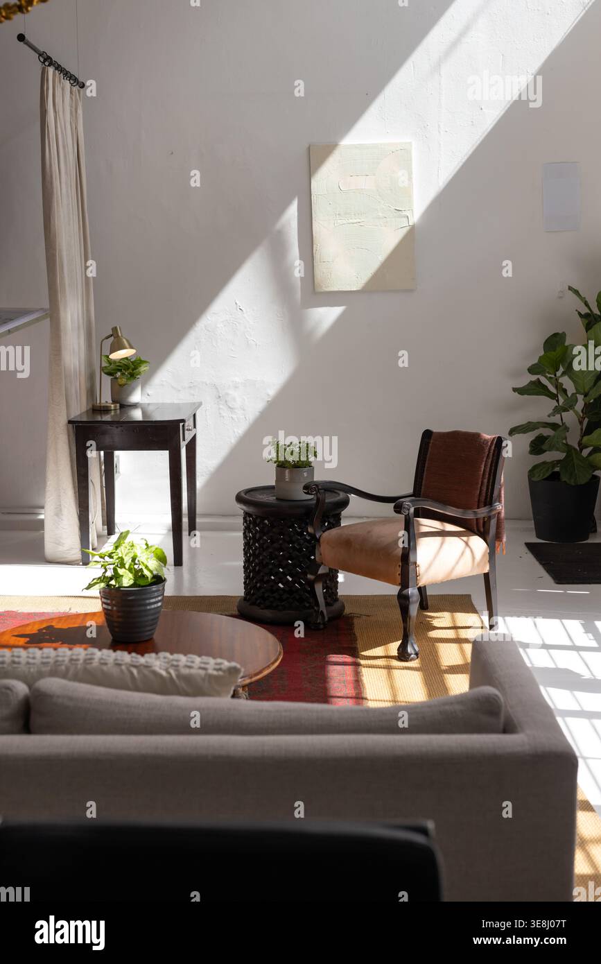 Sunlight casting through window bathing rust armchair, highlighting carved side table, copy space Stock Photo