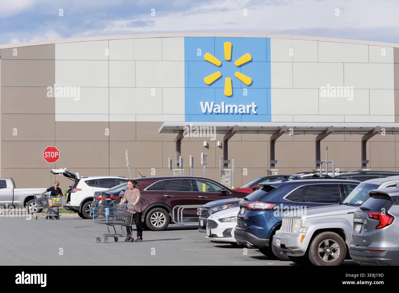 Shoppers with carts in a busy parking lot outside a Walmart Supercenter ...