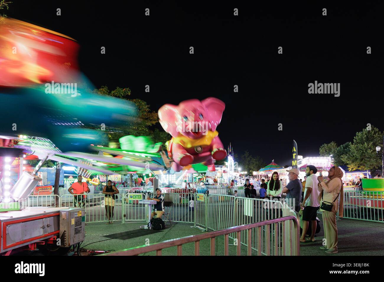 Colorful carnival rides spin at night with crowds at Overpeck Park ...