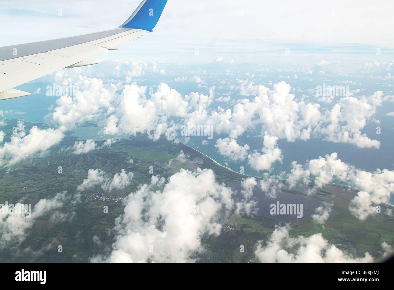 Aut View Aerial view from airplane window with blue and white wing over tropical ...