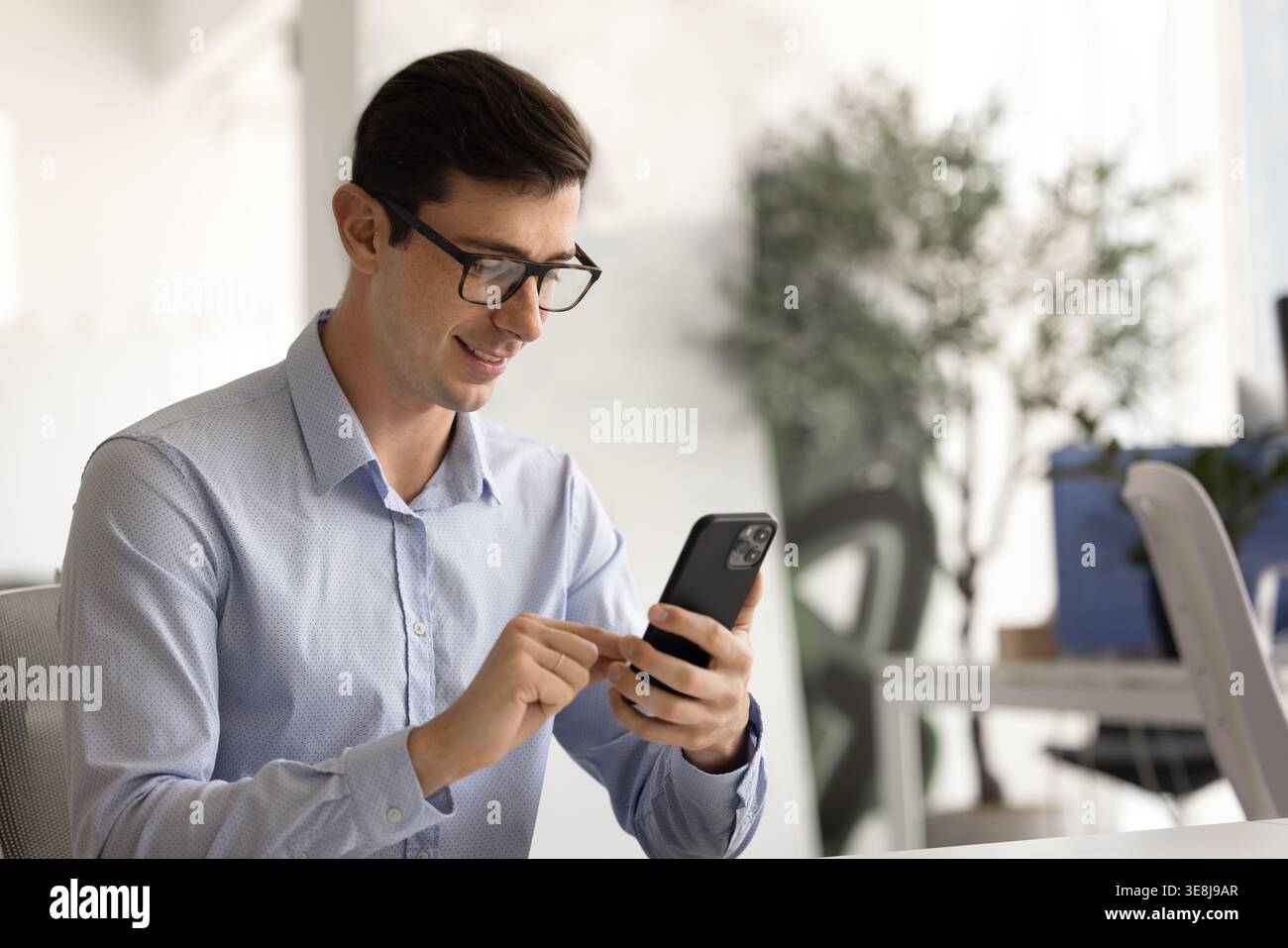 Smiling businessman using smartphone at workplace desk Stock Photo