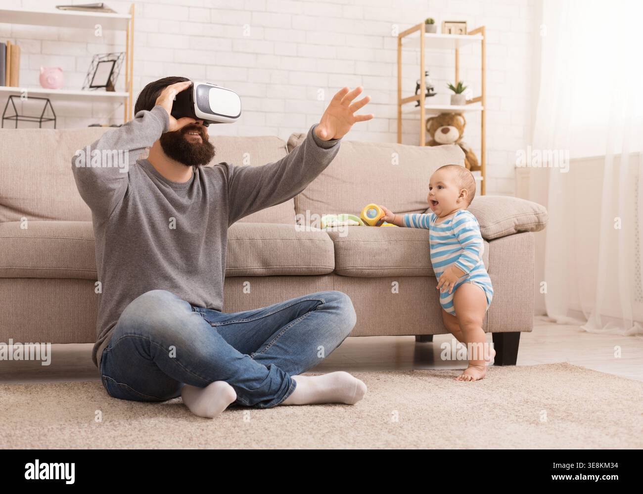 Father using Virtual reality headset, sitting with baby Stock Photo