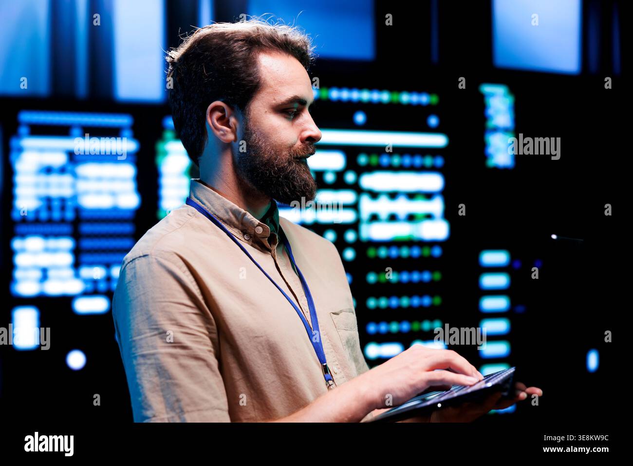 Focused serviceman checking functional blade servers in computer network security data hub. High tech facility infrastructure providing processing and memory resources for computational operations Stock Photo