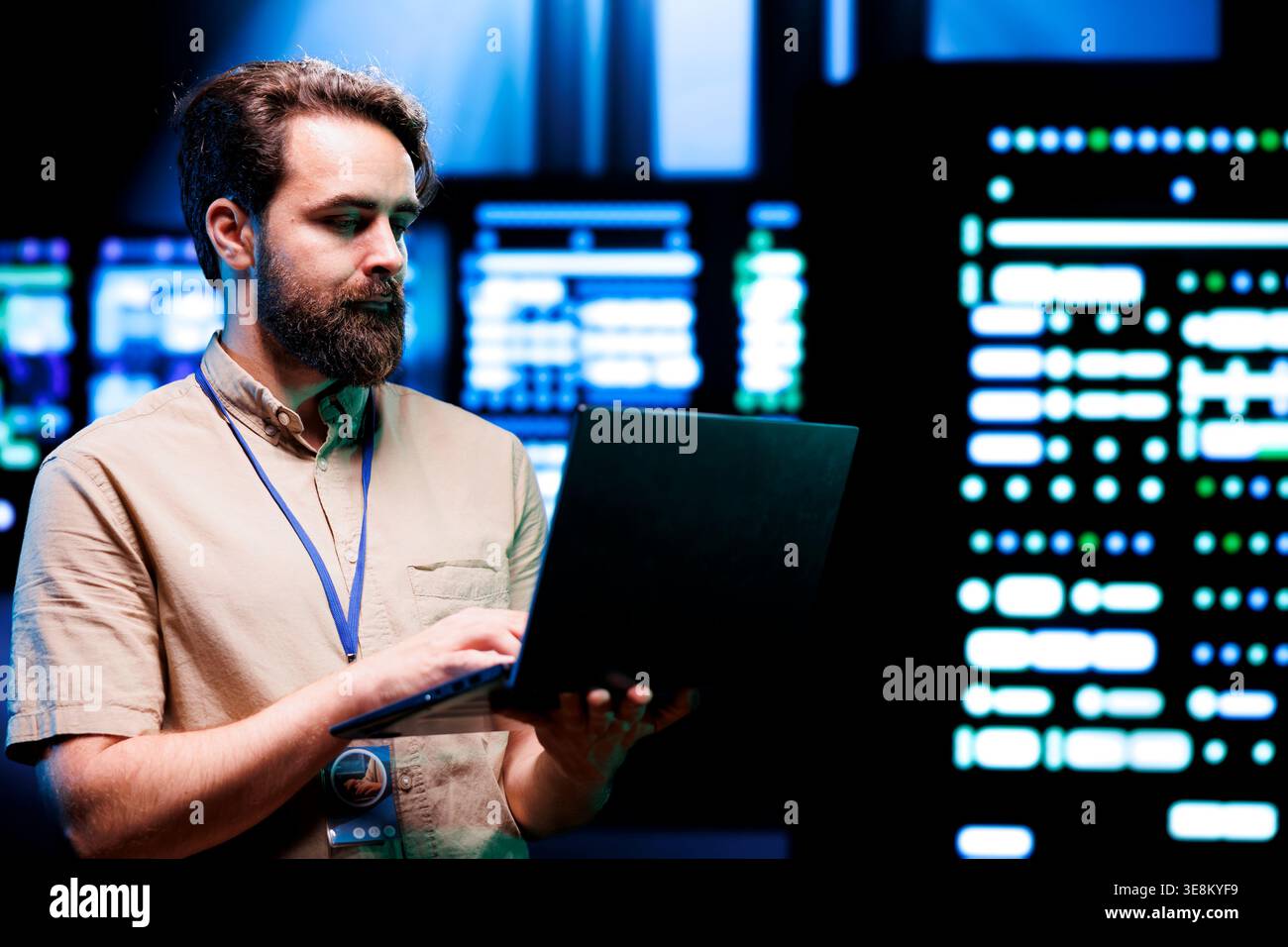 System administrator using laptop to check high tech server rigs. Rackmounts in computer network security data center establishment providing processing and memory resources needed for workloads Stock Photo