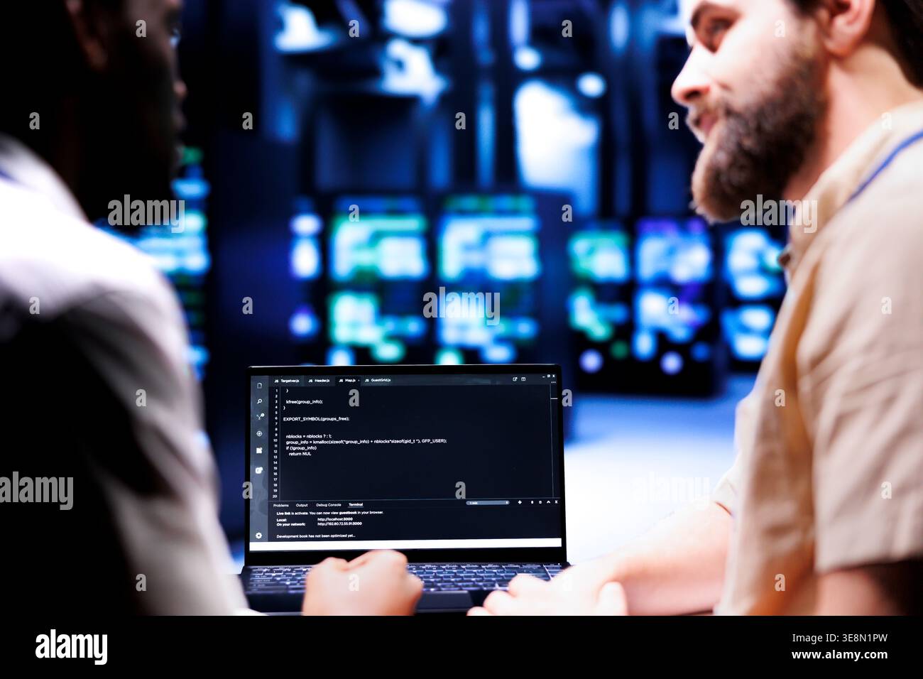 Colleagues updating server clusters, writing complex binary code scripts on laptop terminal. Admins using JavaScript, Java, and database programming to fortify security and safeguard data Stock Photo