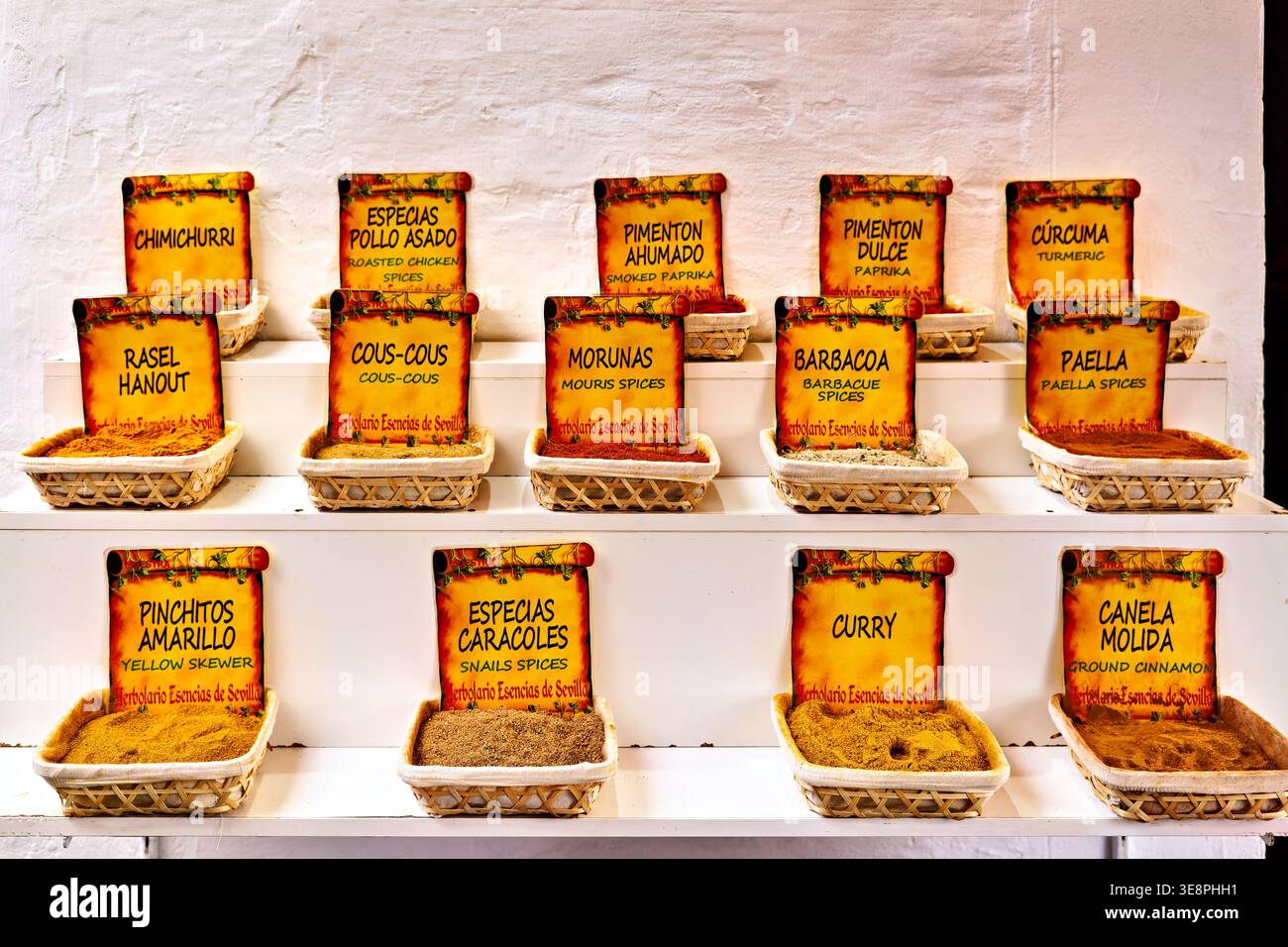 Customers browse a colorful display of spices at a market in Seville, Andalusia. This scene captures local culture and commerce. Stock Photo