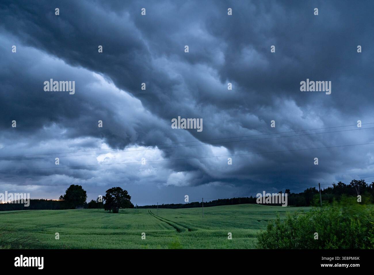 Dramatic storm clouds over green field Stock Photo