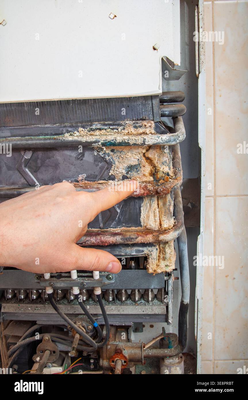 A technician's finger highlights severe mineral buildup and rust on the ...