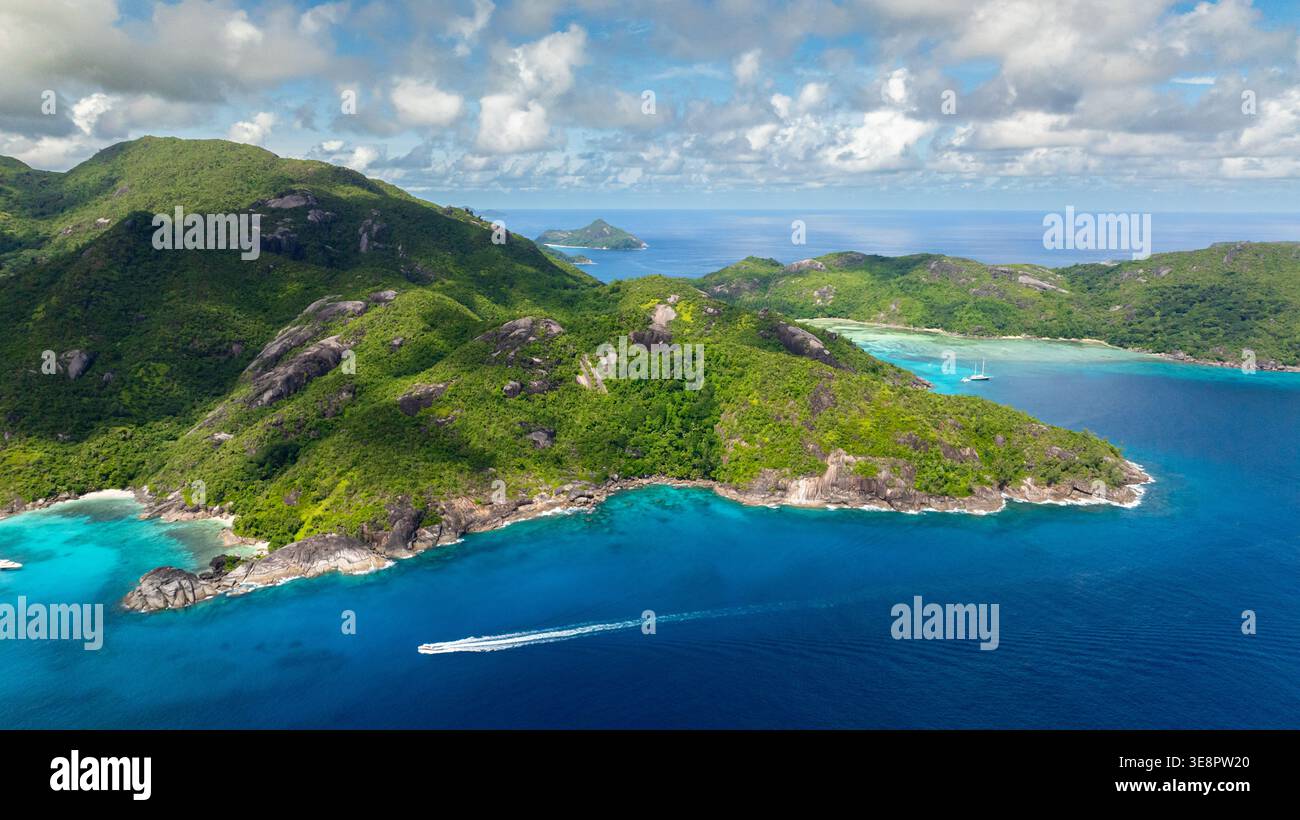 Coastline with lush green mountains descending into turquoise waters. Seychelles, Mahe. Stock Photo