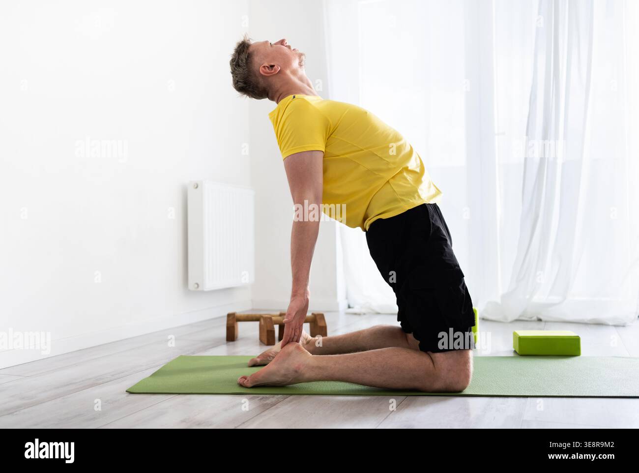 Sporty Young Man Doing Yoga Routine Practice, Standing In Camel Pose Stock Photo