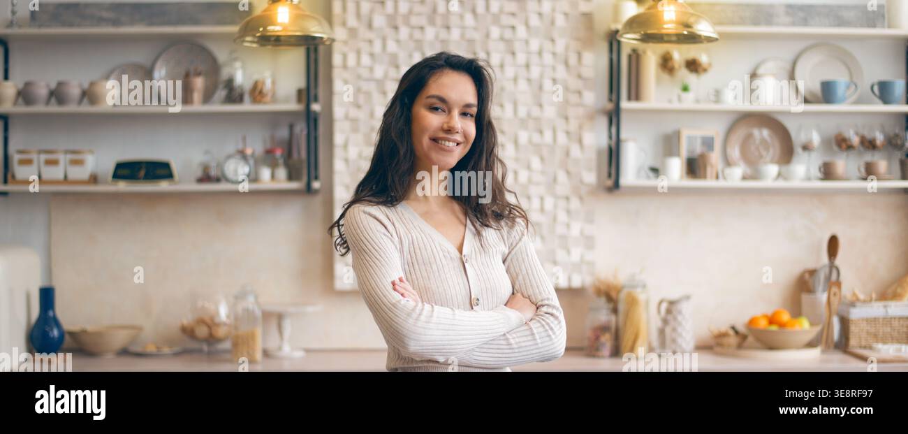 A Young Woman Smiles While Standing in a Kitchen Stock Photo