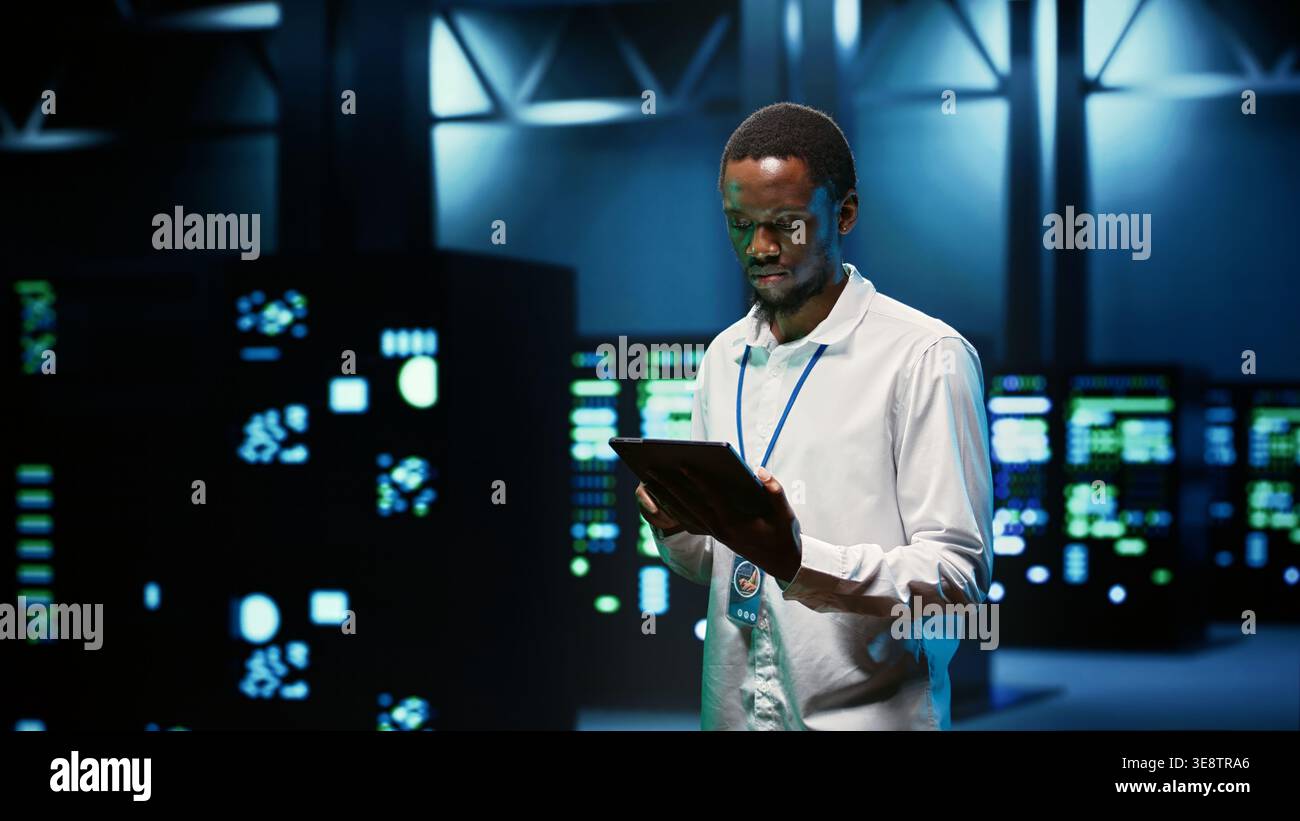 IT programmer in server hub using tablet to find firewall misconfigurations affecting mainframes performance and connectivity, leading to slow data transfer rates and poor client communication Stock Photo