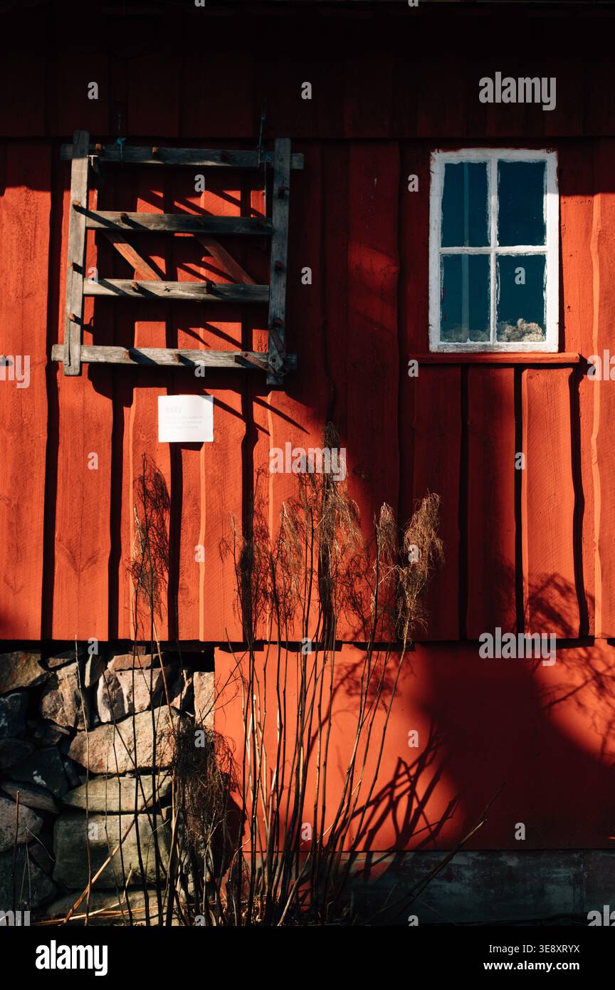 Rustic old red barn wood plank wall with small window with white frame background Stock Photo