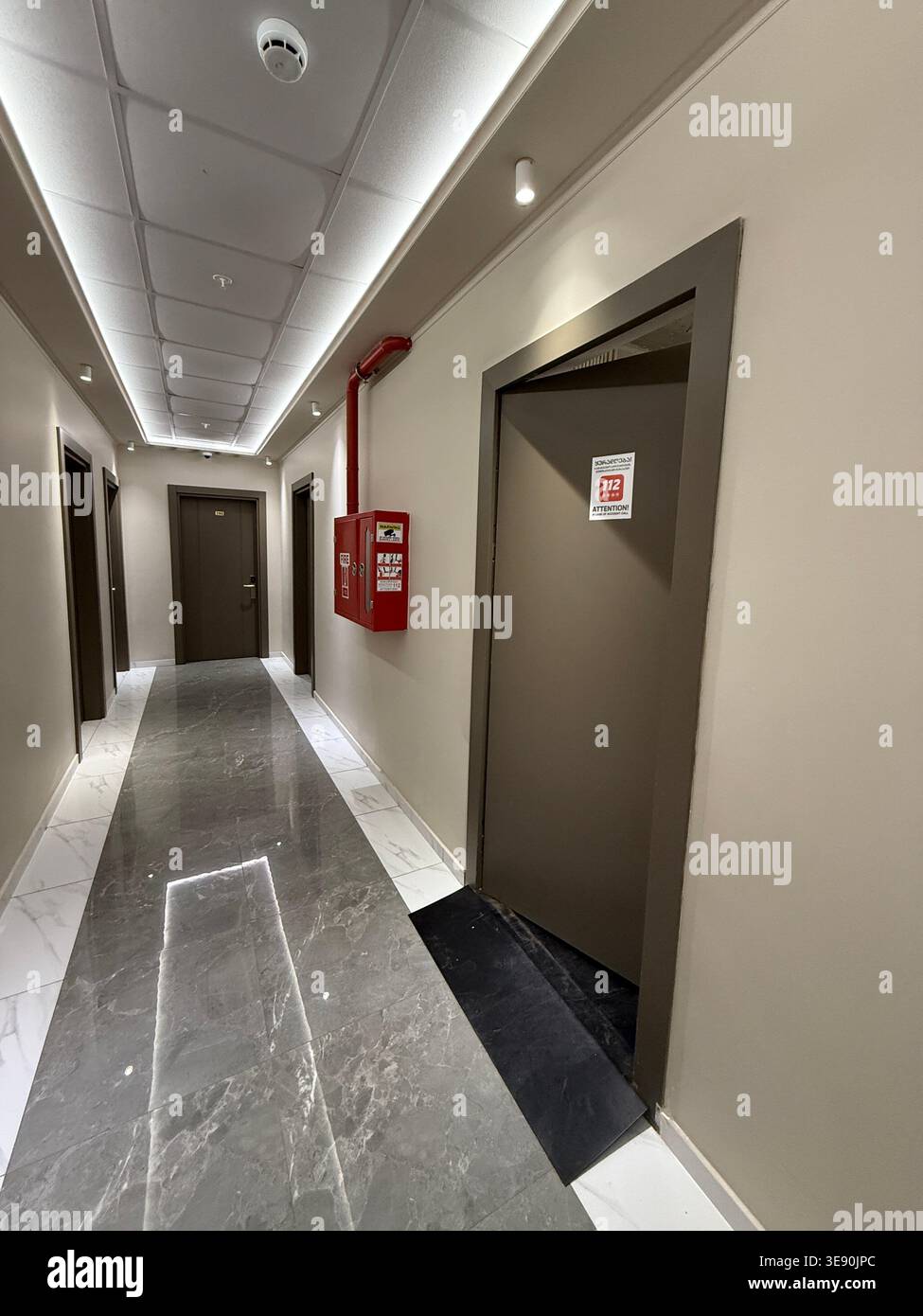 Fire exit door and safety equipment in modern building hallway with marble floor, emergency concept. Mobile photo Stock Photo