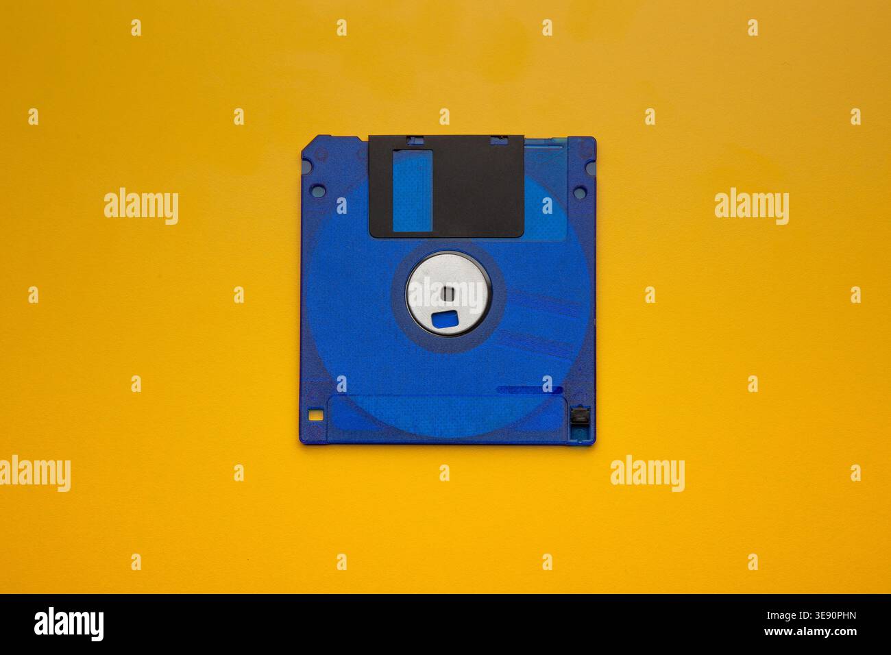 Blue floppy disk centered on yellow background Stock Photo